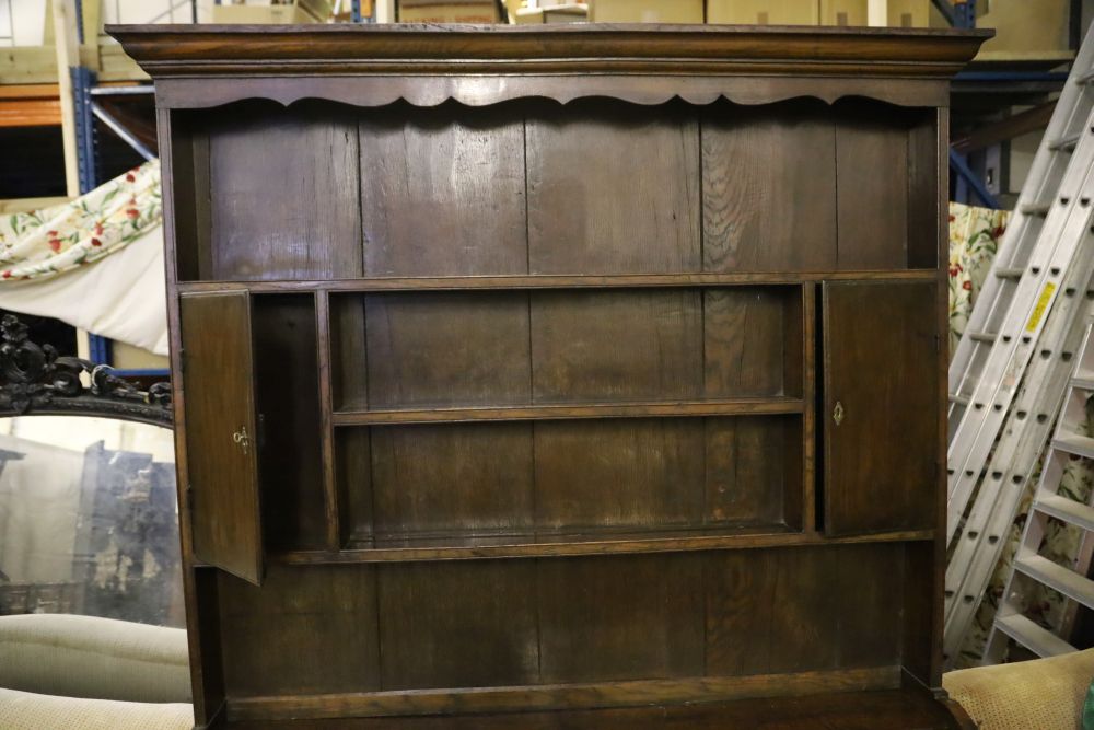 A mid-18th century oak dresser having later boarded plate rack over short drawers and panelled doors, width 151cm, depth 43cm, height 2